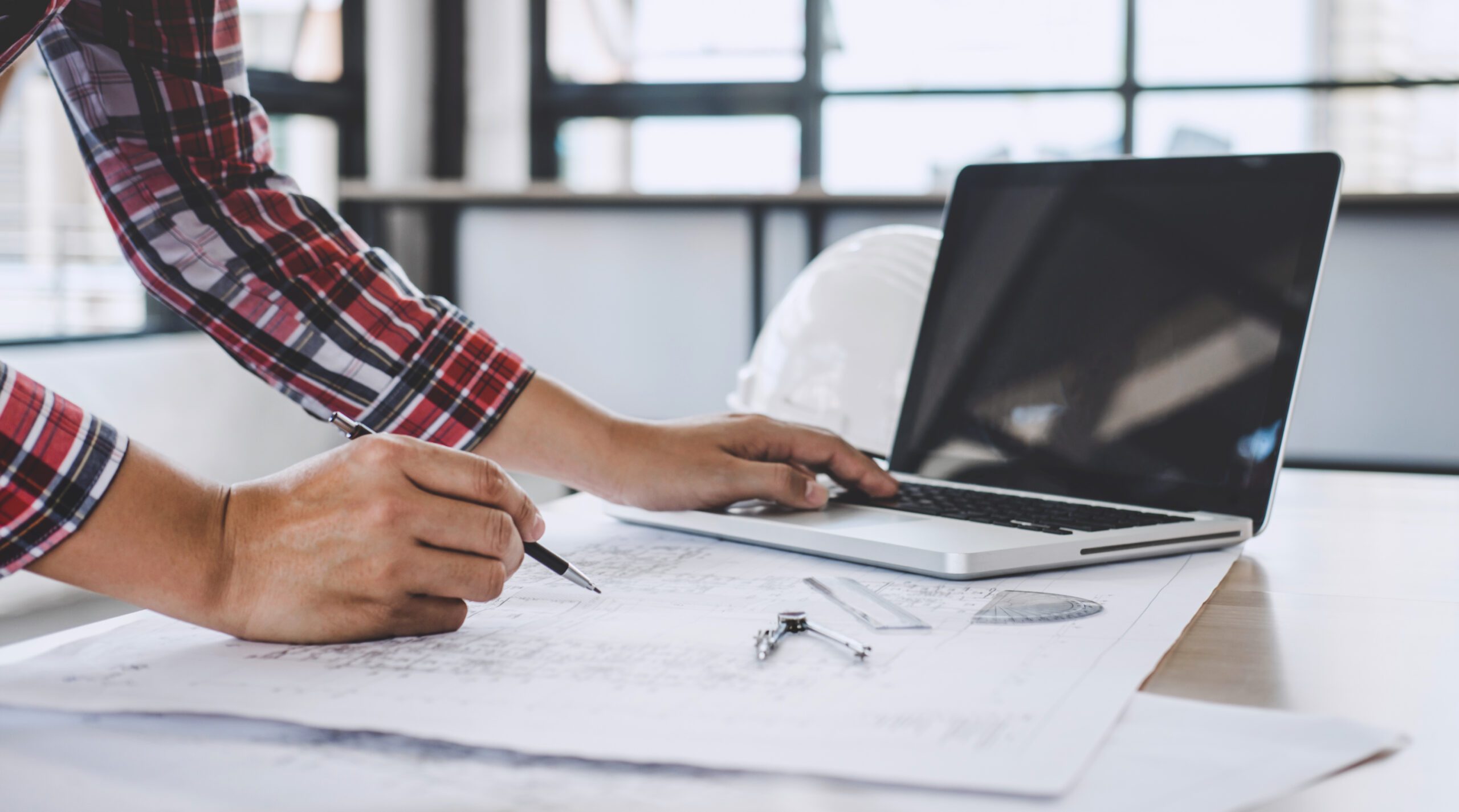 Engineer reviewing technical drawings and working on a laptop, representing Chema Foam’s technical services 